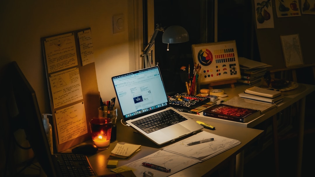 Desk with laptop, books, and lit candle.