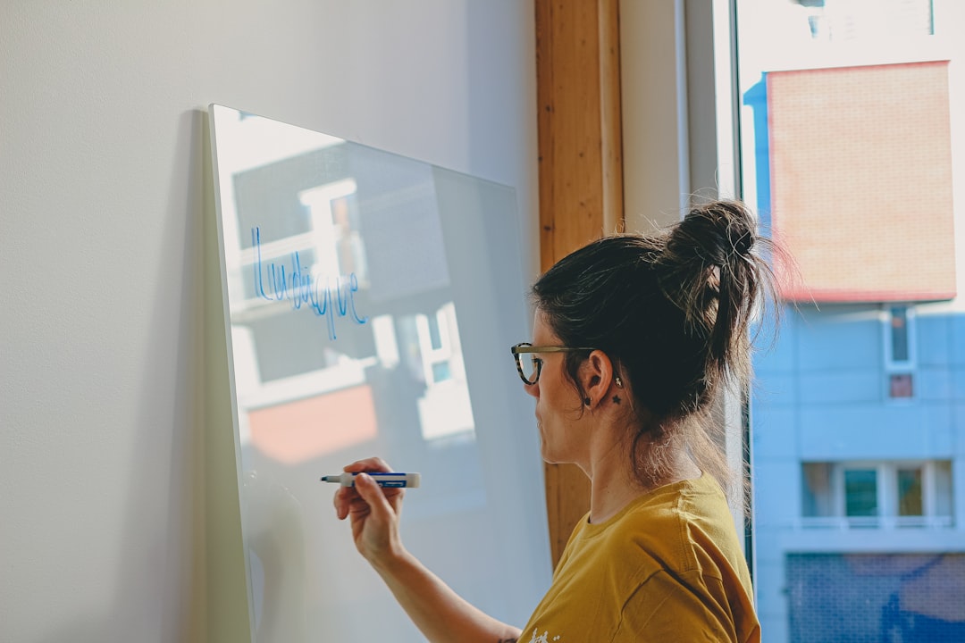 Woman writing on a whiteboard by the window