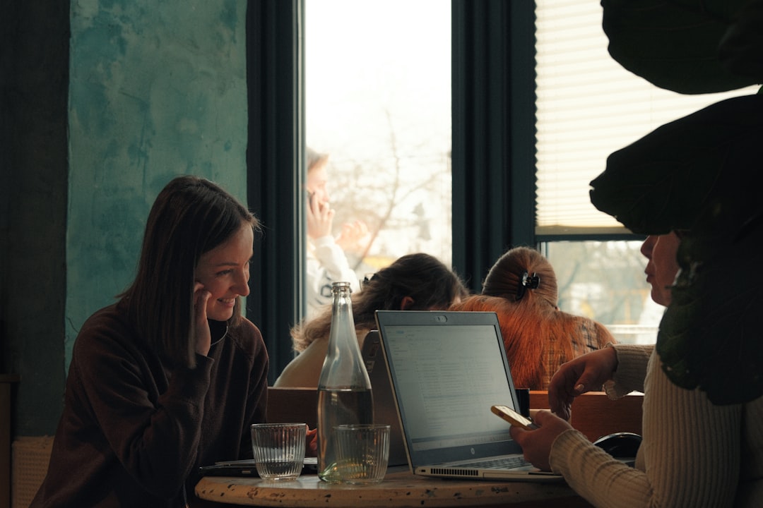 Two women talk at a table with a laptop