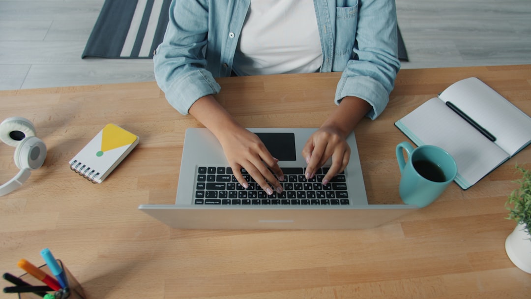 Person typing on a laptop at a wooden desk