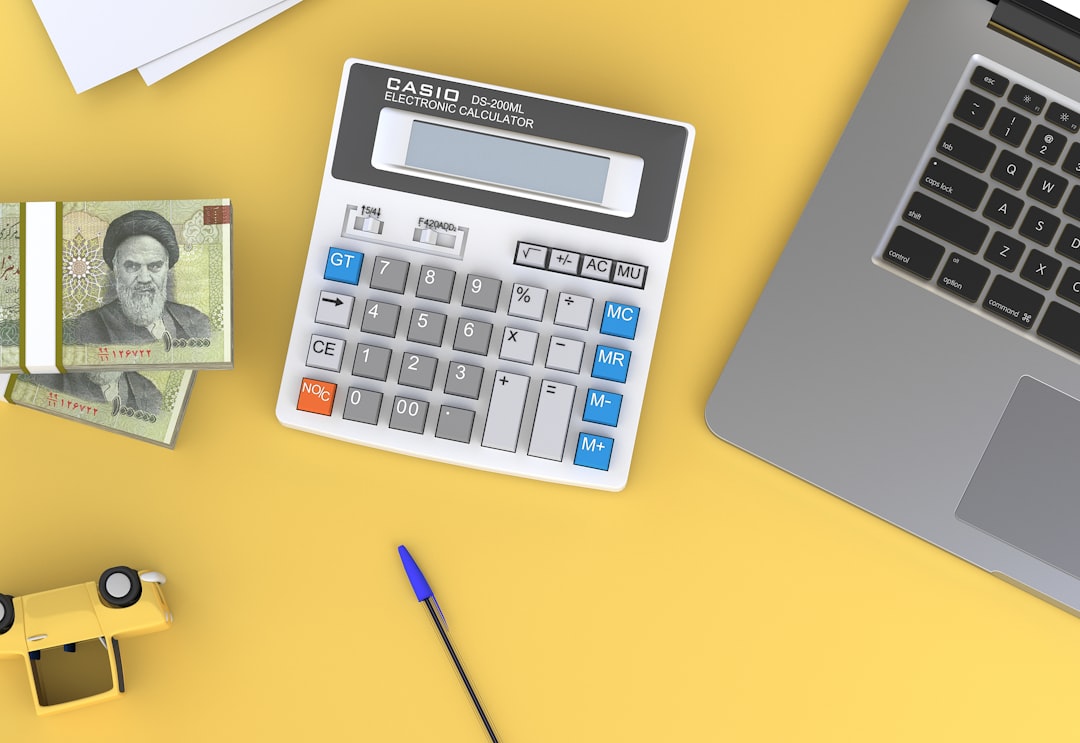 Calculator and laptop on a desk for checking reasoning tokens cost while coding and building a solo AI stack