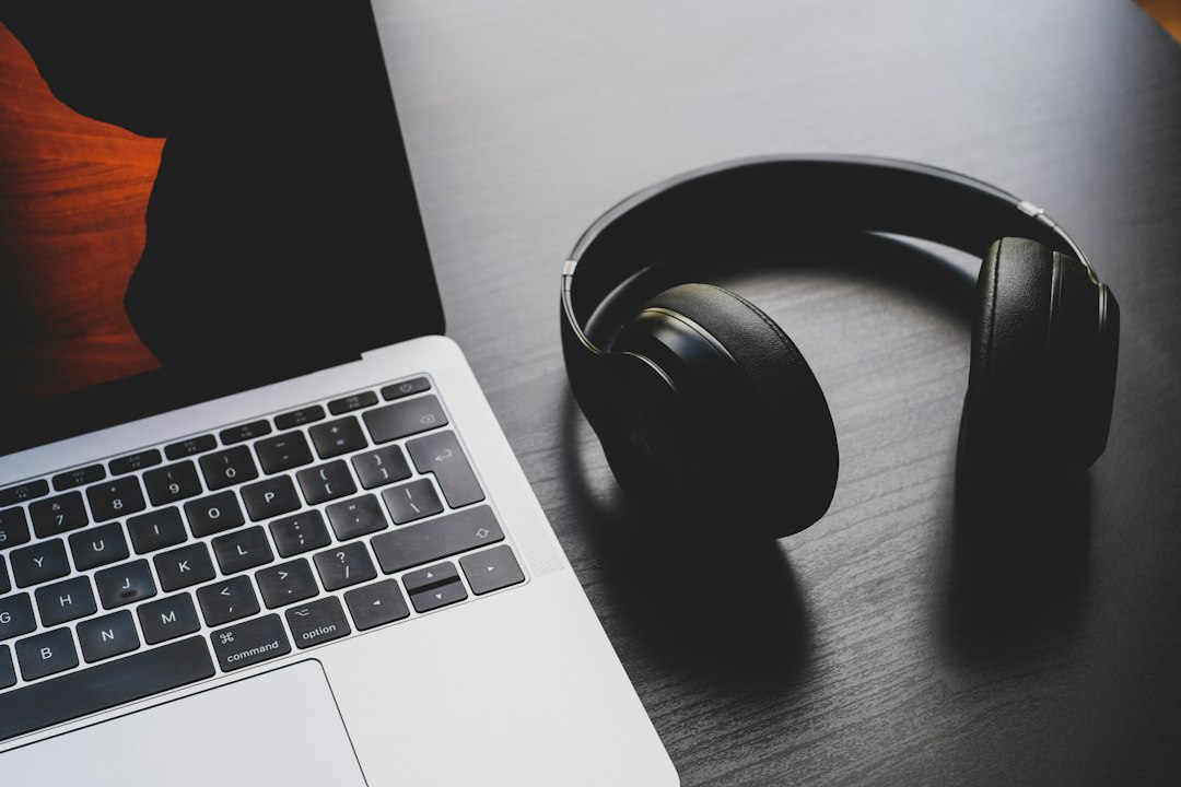 Voxtral 3 call transcription for productivity: headphones beside a laptop on a dark desk